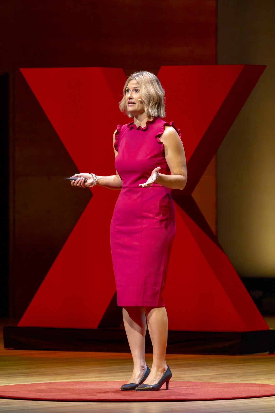 Katherine gesturing as she speaks beside the TEDx X