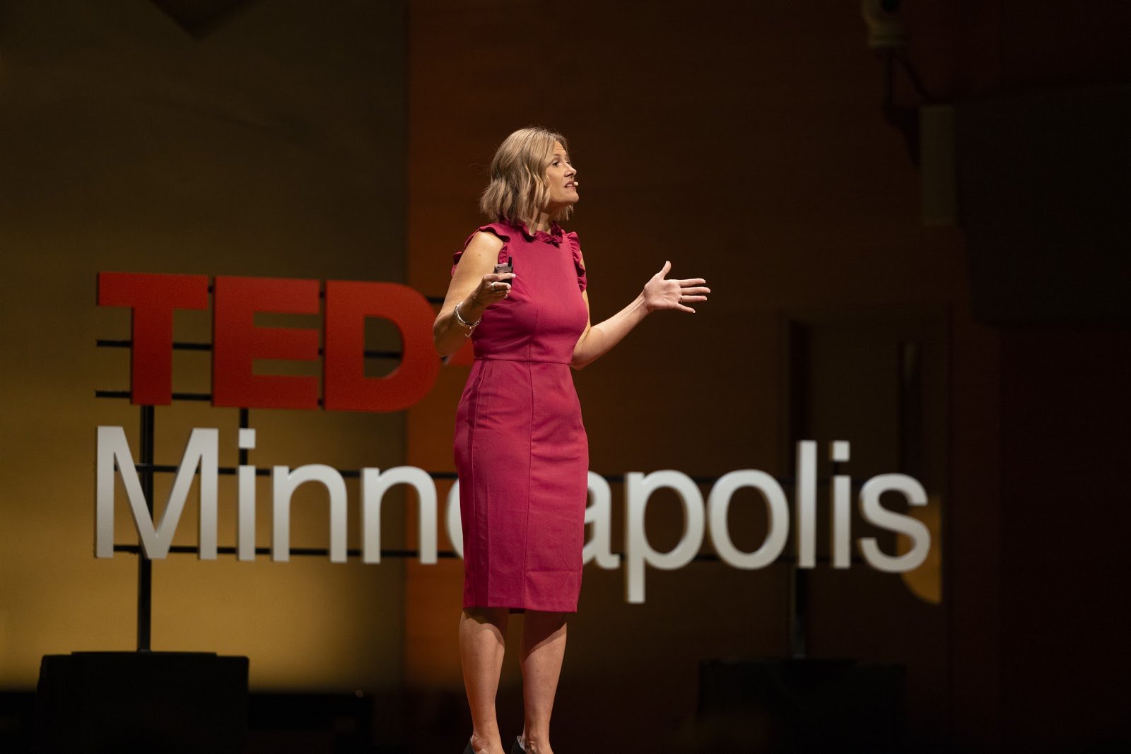 Katherine with arms open while speaking on the TEDx stage