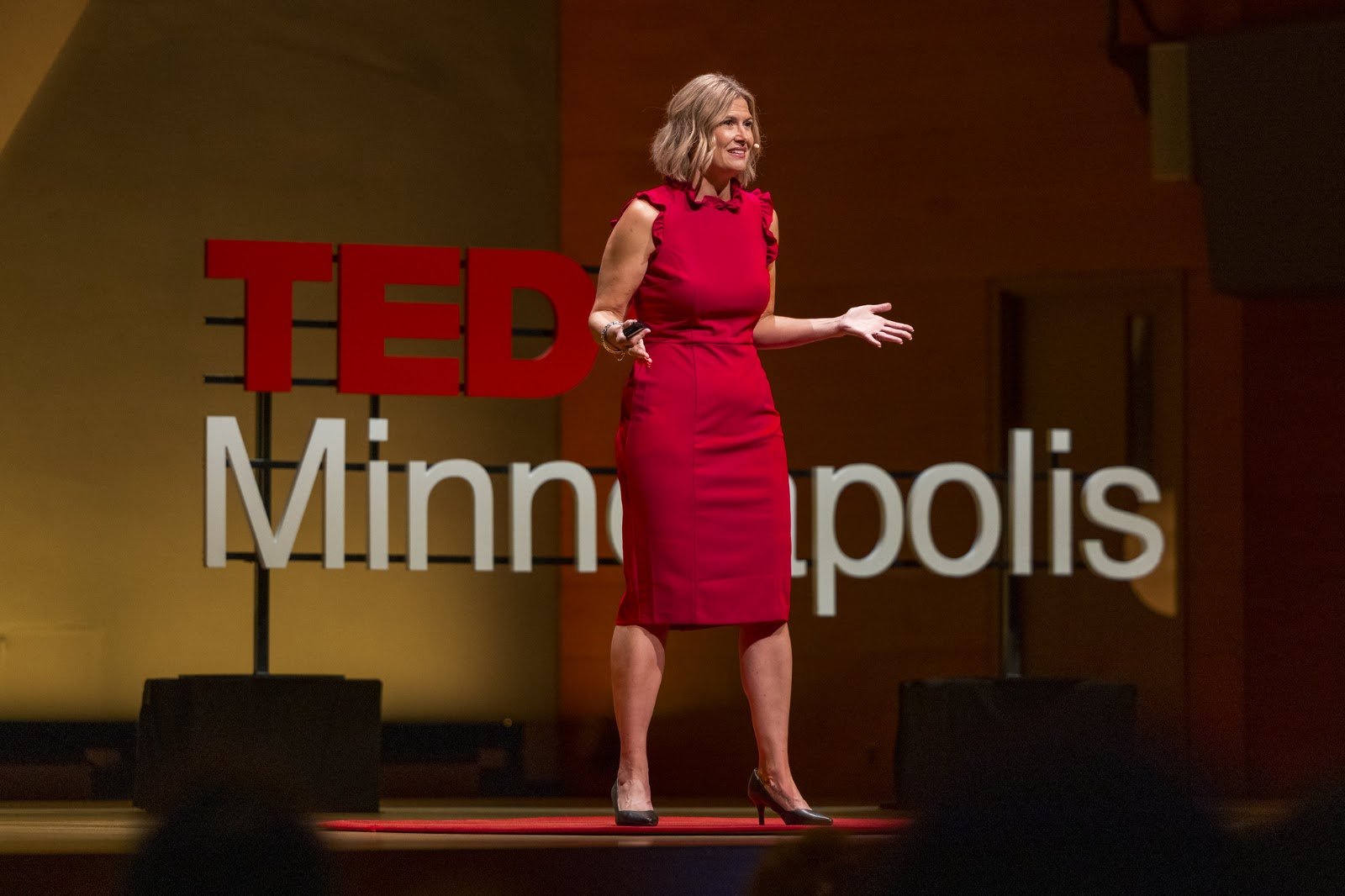 Katherine mid-sentence in front of the TEDxMinneapolis sign