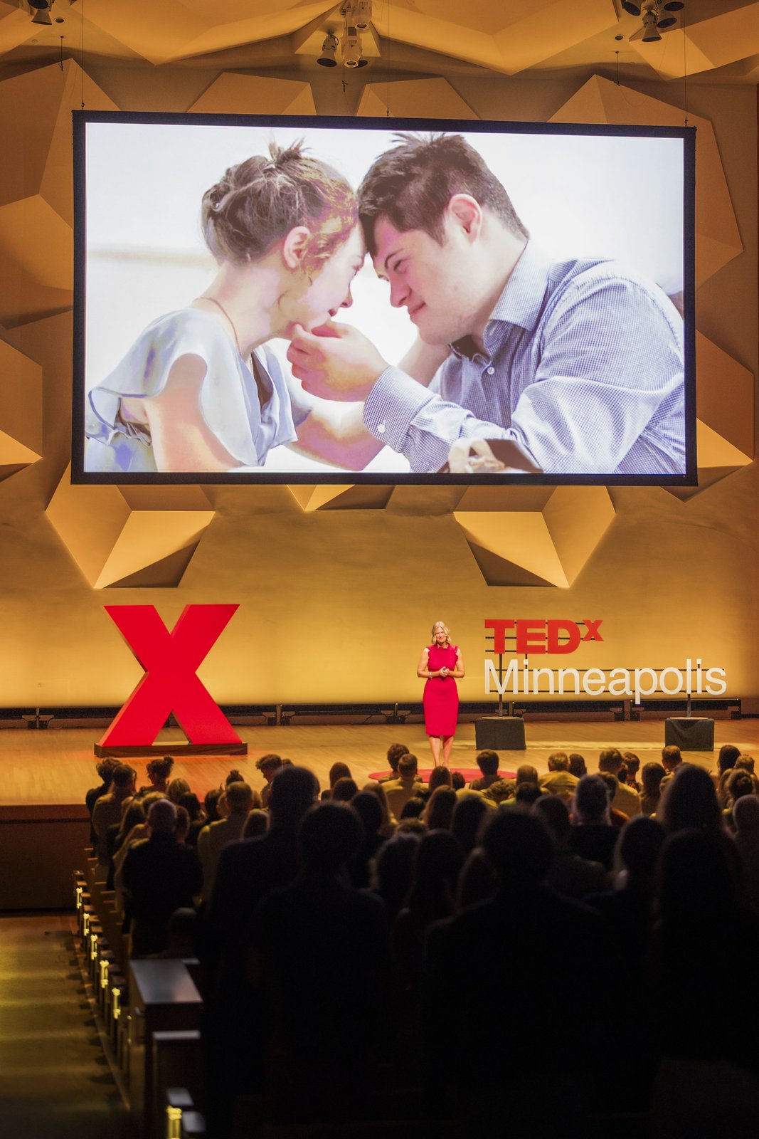A couple pictured on the TEDx screen above the audience