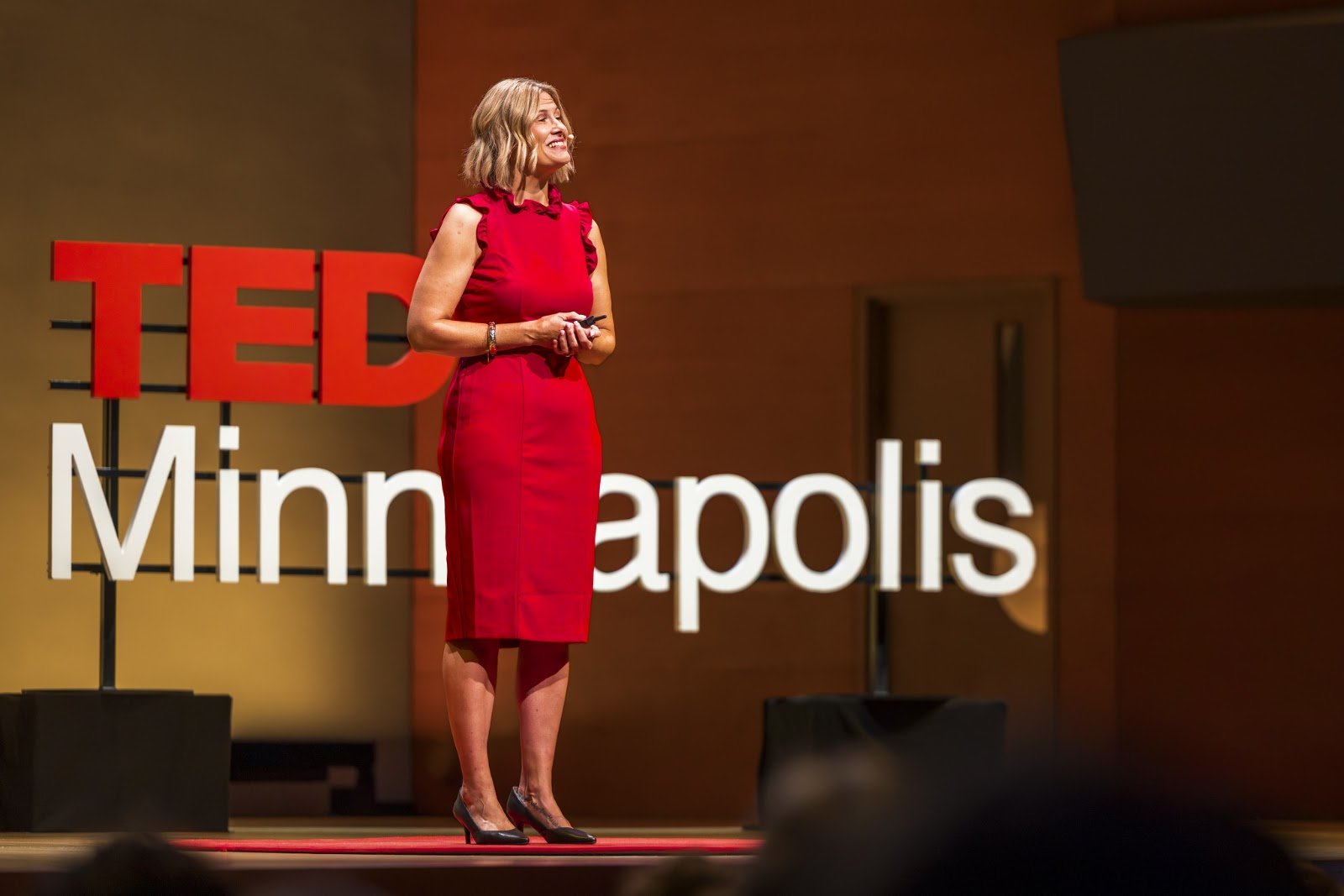 Katherine speaking in front of the TEDxMinneapolis stage sign