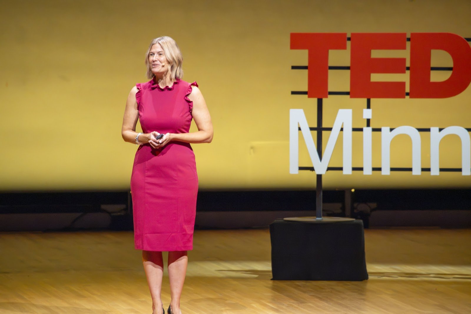 Katherine on stage in front of the illuminated TEDxMinneapolis letters