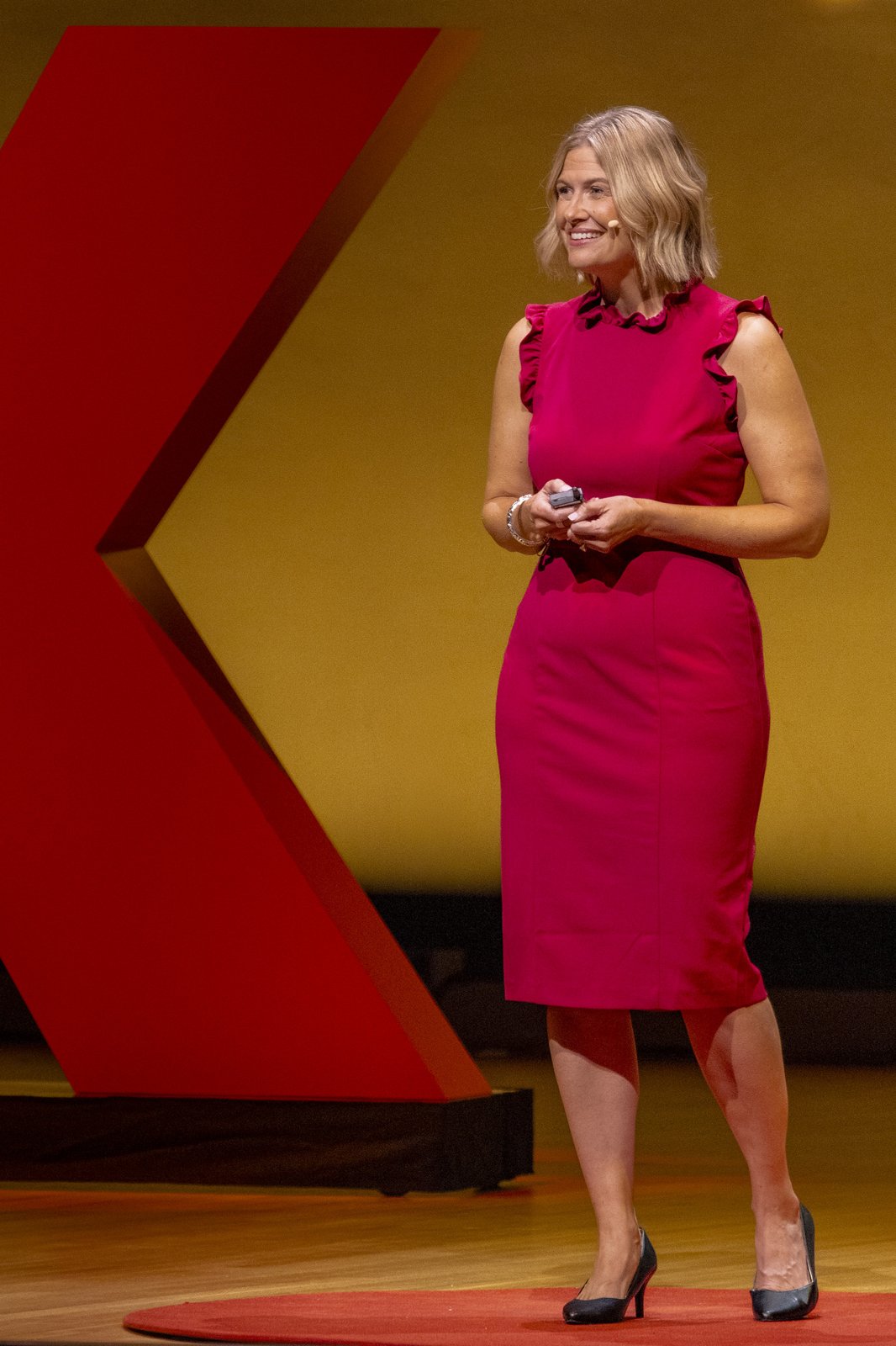 Katherine standing on the TEDx stage beside the red X
