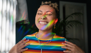 Neurodivergent woman in rainbow shirt smiling